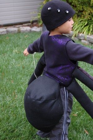 a young boy is playing with an inflatable ball on the grass, wearing a black hat and purple shirt