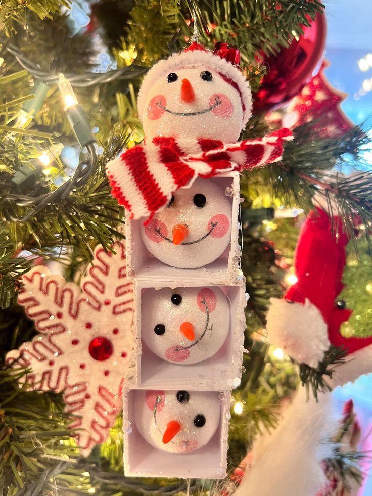 an ornament hanging from a christmas tree decorated with snowmen