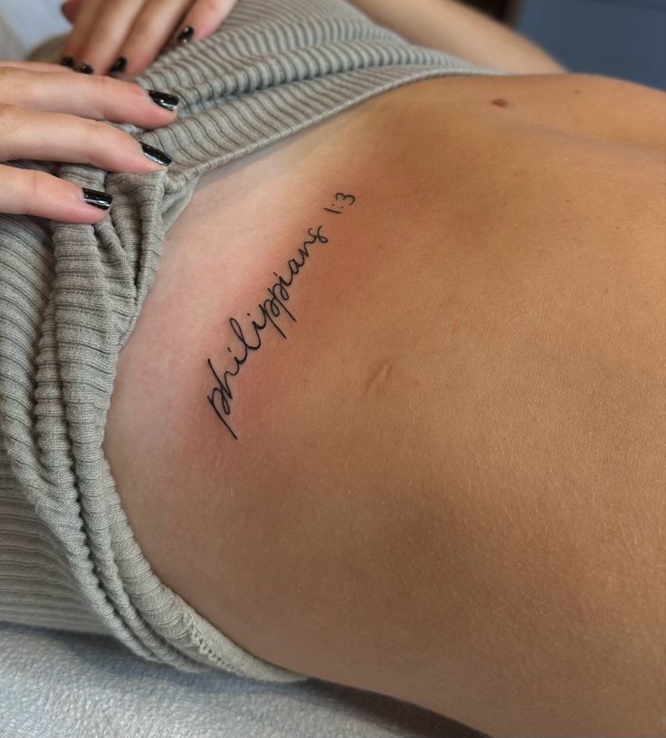 a woman with a tattoo on her stomach is laying down and holding onto the arm