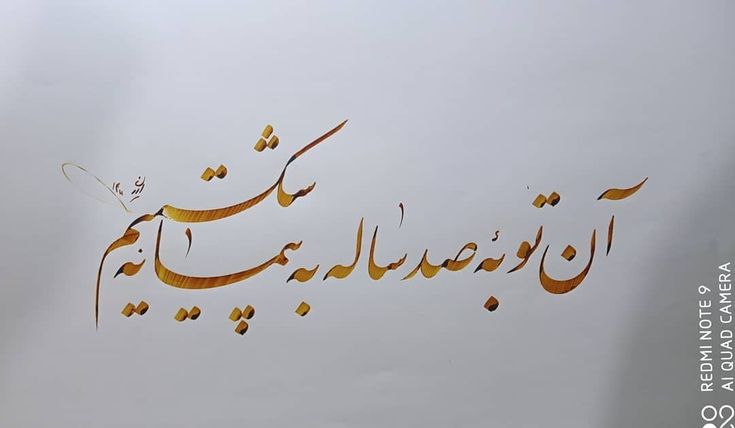 arabic calligraphy written in gold on a white background