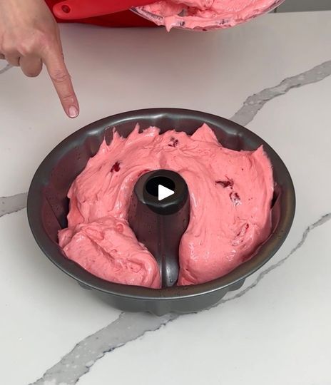 someone is mixing pink cake batter in a pan