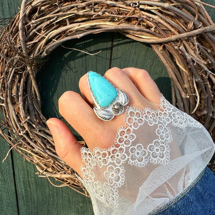 This unique ring features a sweet and soft all natural turquoise stone set in a sterling silver band. The stone is encased in a scalloped bezel and complemented by a rose and two leaves. The floral split shank allows for a ring size of 7-7.5. This one-of-a-kind design is sure to make a statement and cannot be resized. -Details- • Materials : sterling silver and all natural turquoise. • Measurements : 2" long by 1.25" wide.• Ring size: will easily fit a size 7-7.5. (cannot be resized) Please fami Adjustable Turquoise Open Ring For Wedding, Bohemian Sterling Silver Turquoise Wedding Ring, Oval Turquoise Ring For Wedding, Turquoise Open Ring For Wedding, Turquoise Open Ring Jewelry For Wedding, Elegant Turquoise Open Ring For Wedding, Elegant Adjustable Turquoise Ring With Large Stone, Turquoise Ring With Large Stone For Anniversary, Elegant Turquoise Promise Ring