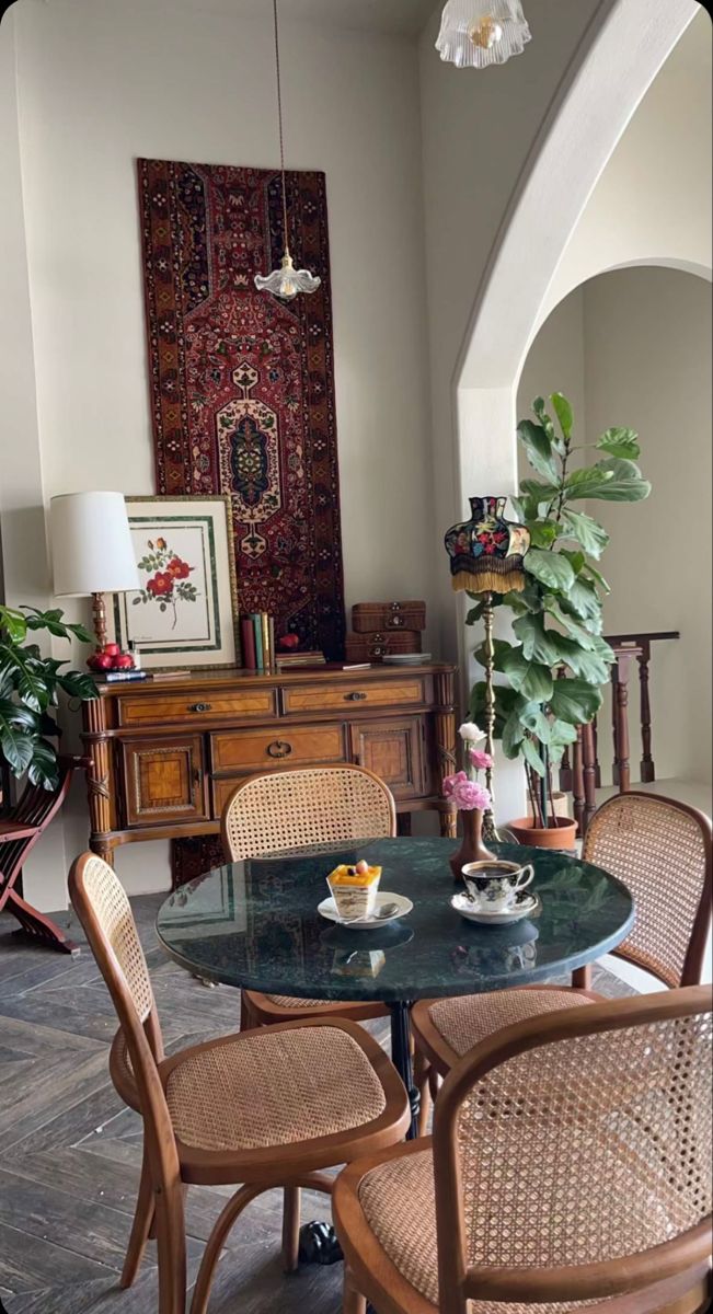 a dining room table with chairs and a rug on the wall