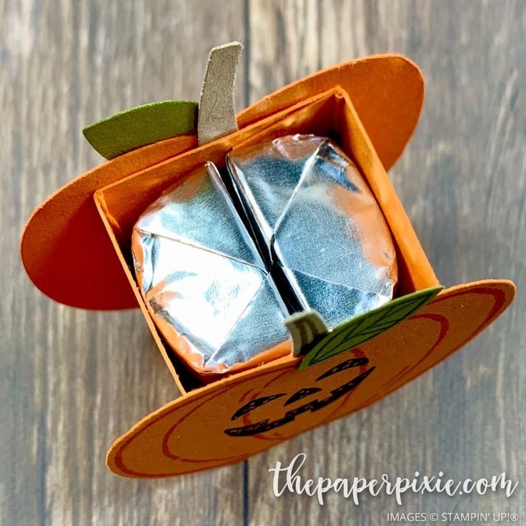 an orange box with two pieces of silver foil in it on top of a wooden table