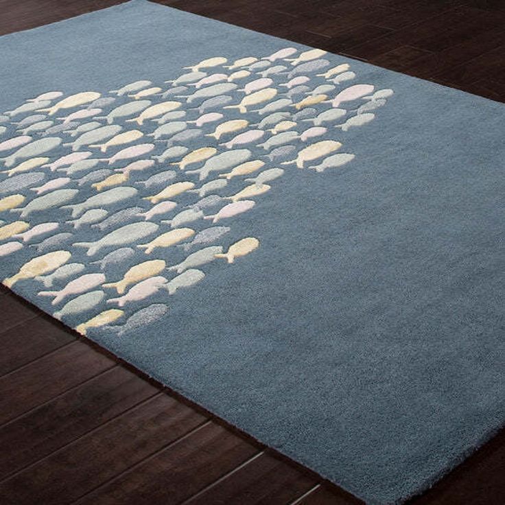 a blue rug with white and yellow fish on it in a living room next to hardwood flooring