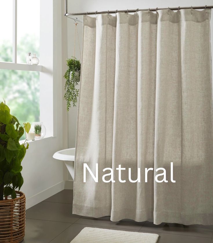 a bathroom with a shower curtain, rug and potted plants