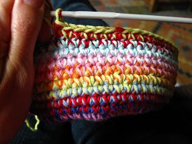 a person holding a crocheted bag with a white knitting needle in the middle