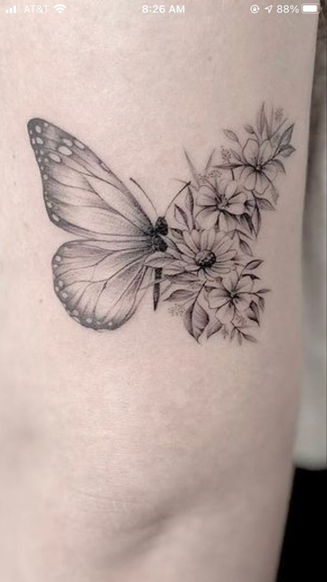 a black and white photo of a butterfly with flowers on it's back thigh