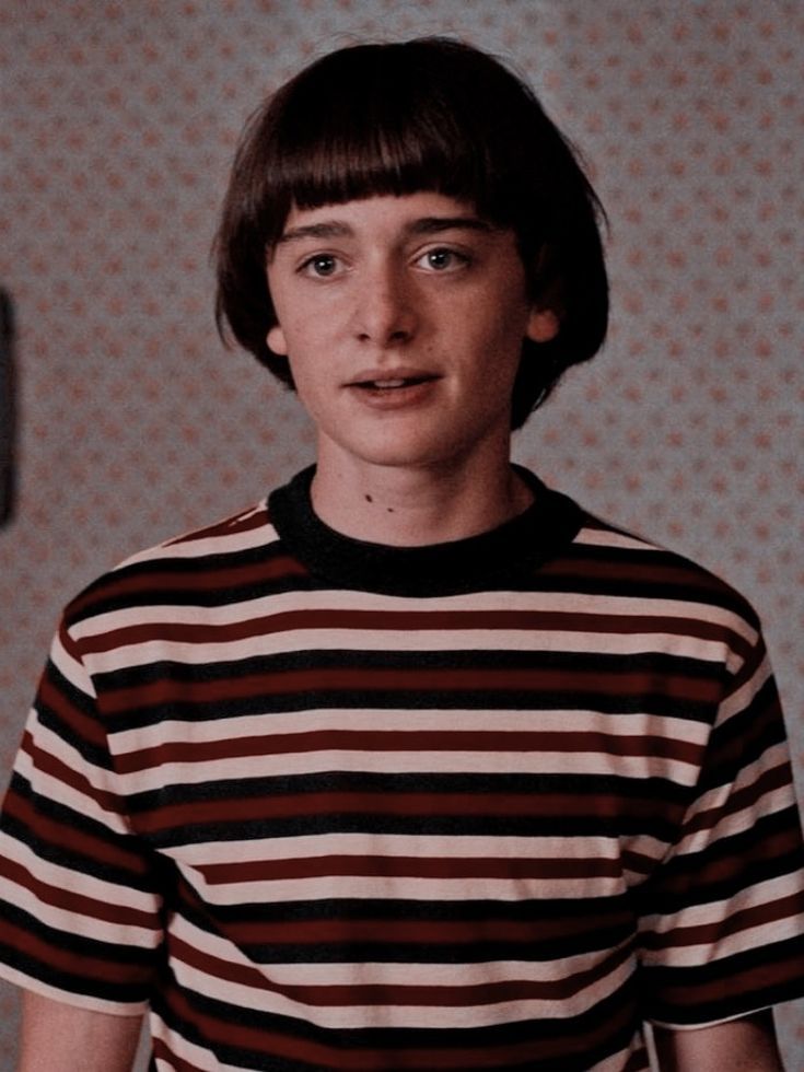 a young man wearing a striped shirt and looking at the camera