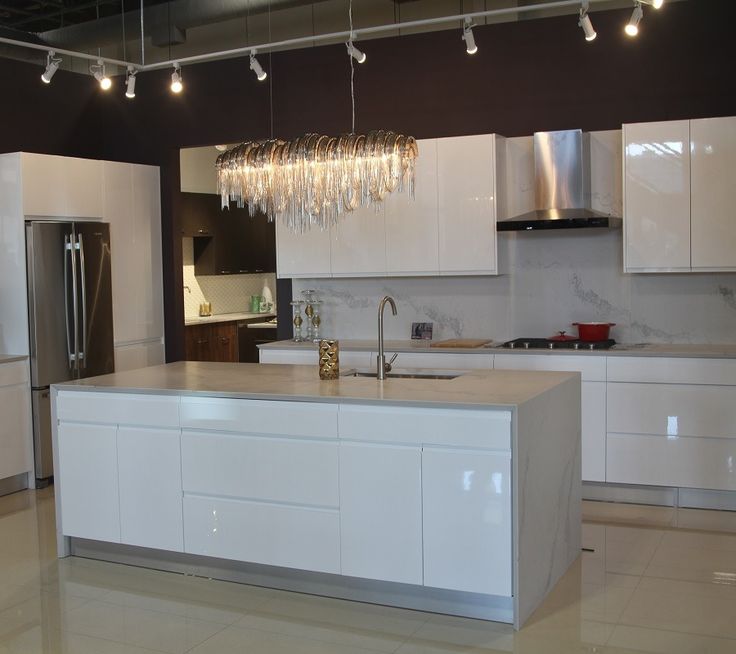 a modern kitchen with white cabinets and stainless steel appliances, chandelier hanging from the ceiling