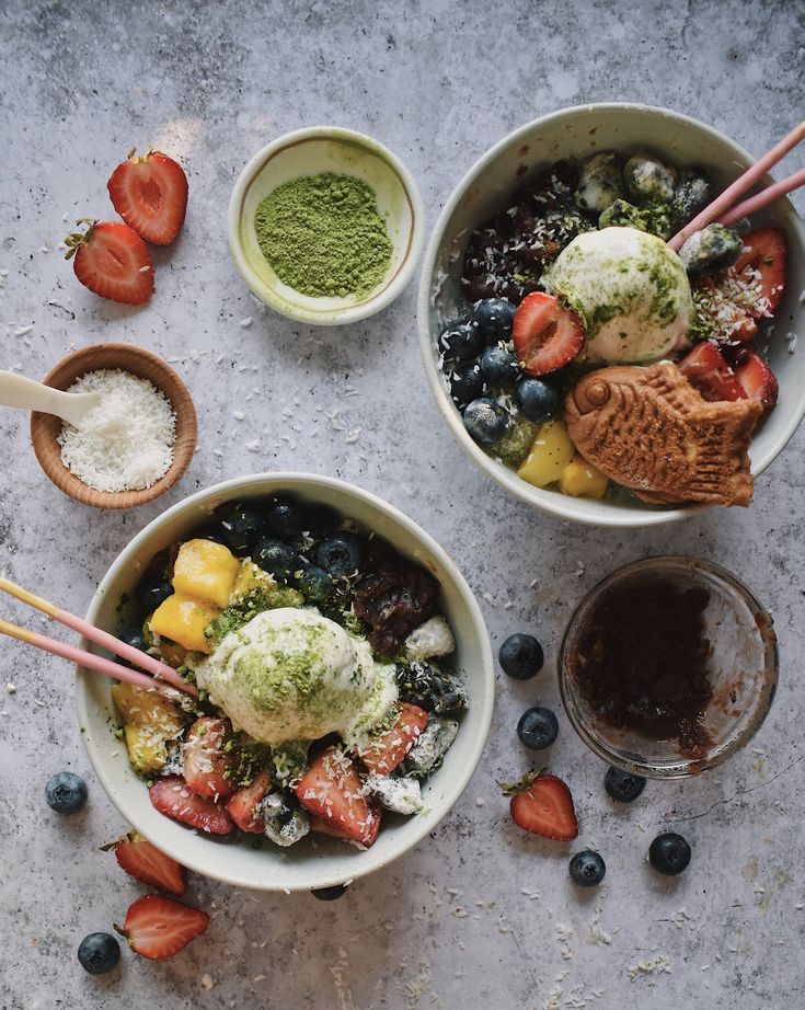 two bowls with strawberries, blueberries, broccoli and other food items