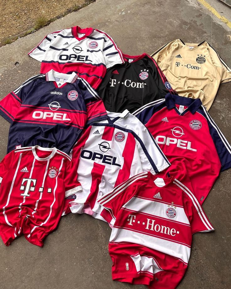 several soccer jerseys laying on the ground next to each other, all different colors and sizes