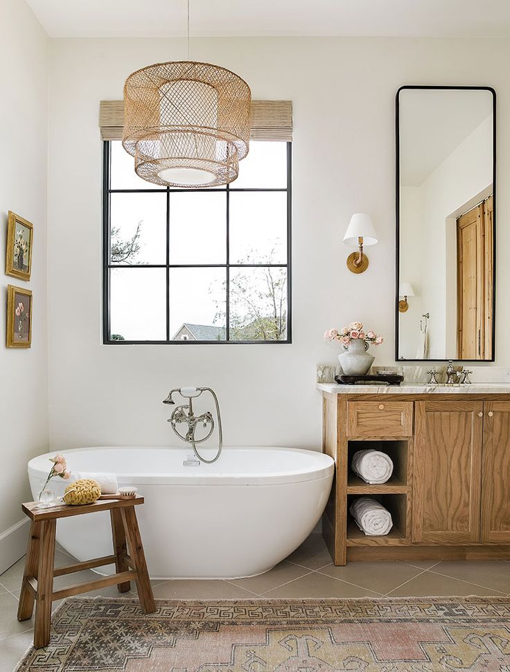 a bathroom with a large white bathtub next to a wooden cabinet and mirror on the wall