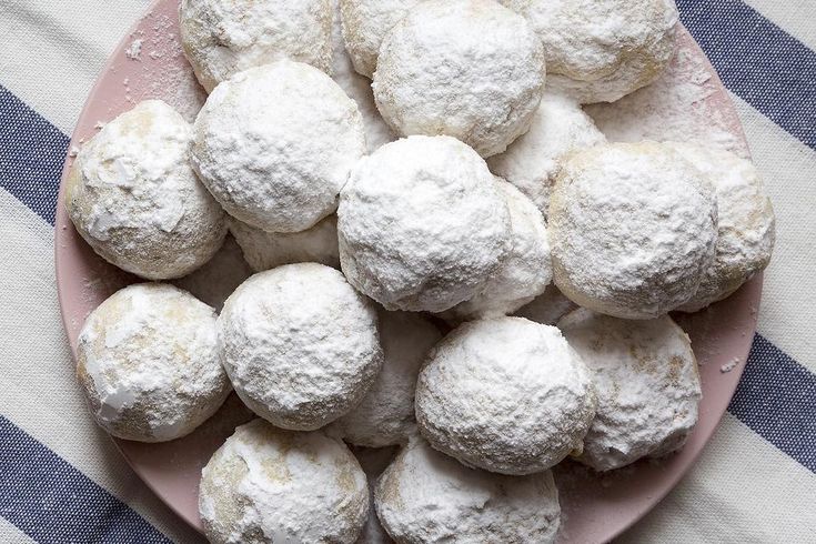 a plate full of powdered sugar cookies on a blue and white striped tablecloth