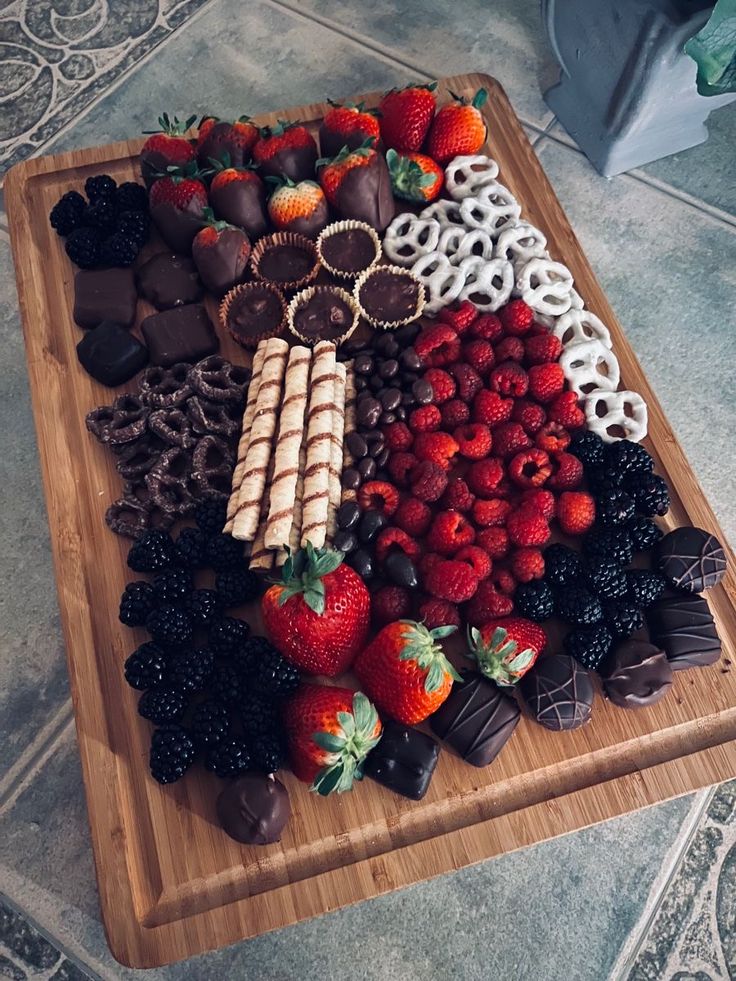 an assortment of chocolates and strawberries on a cutting board with pretzels