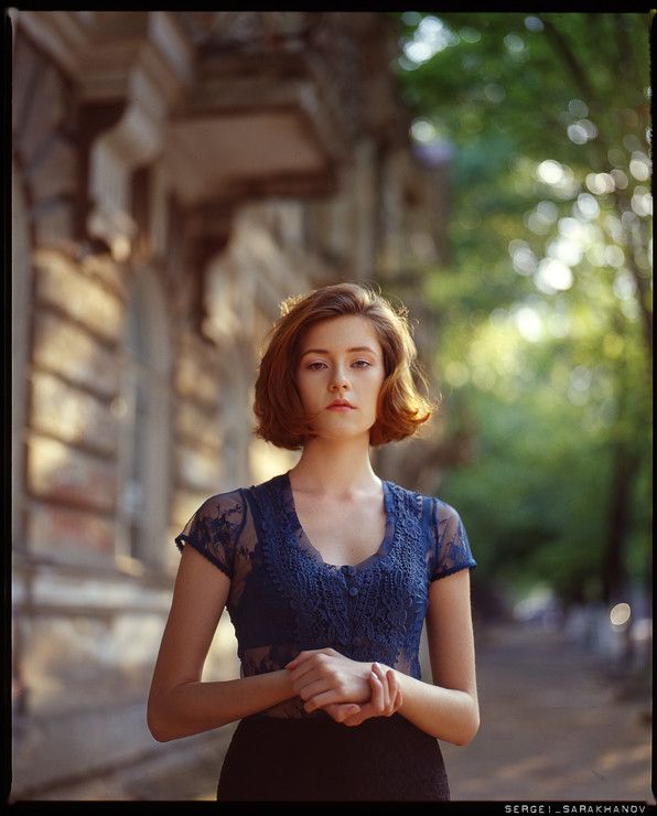 a woman standing in front of an old building with her hands clasped to her chest