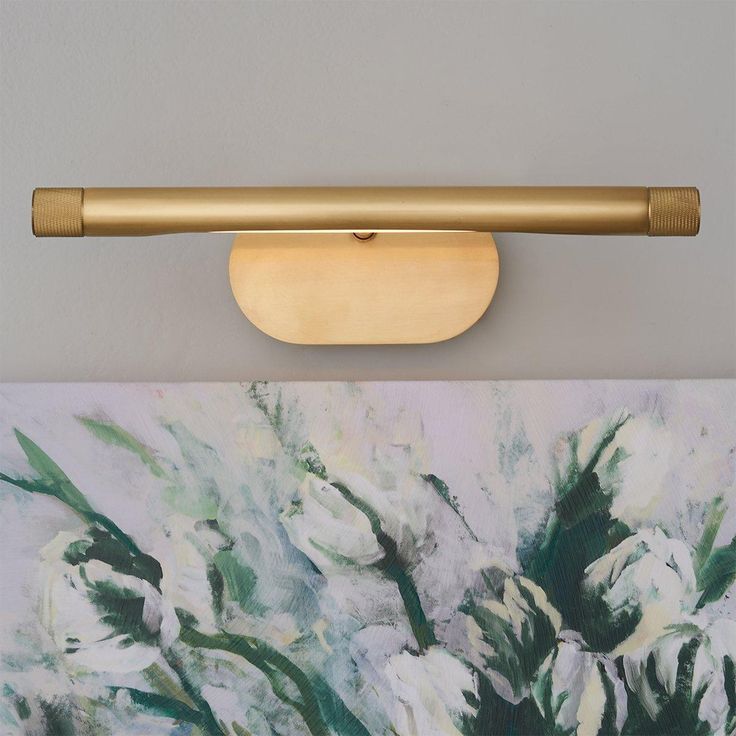 a painting is hanging on the wall next to a light fixture with a gold handle