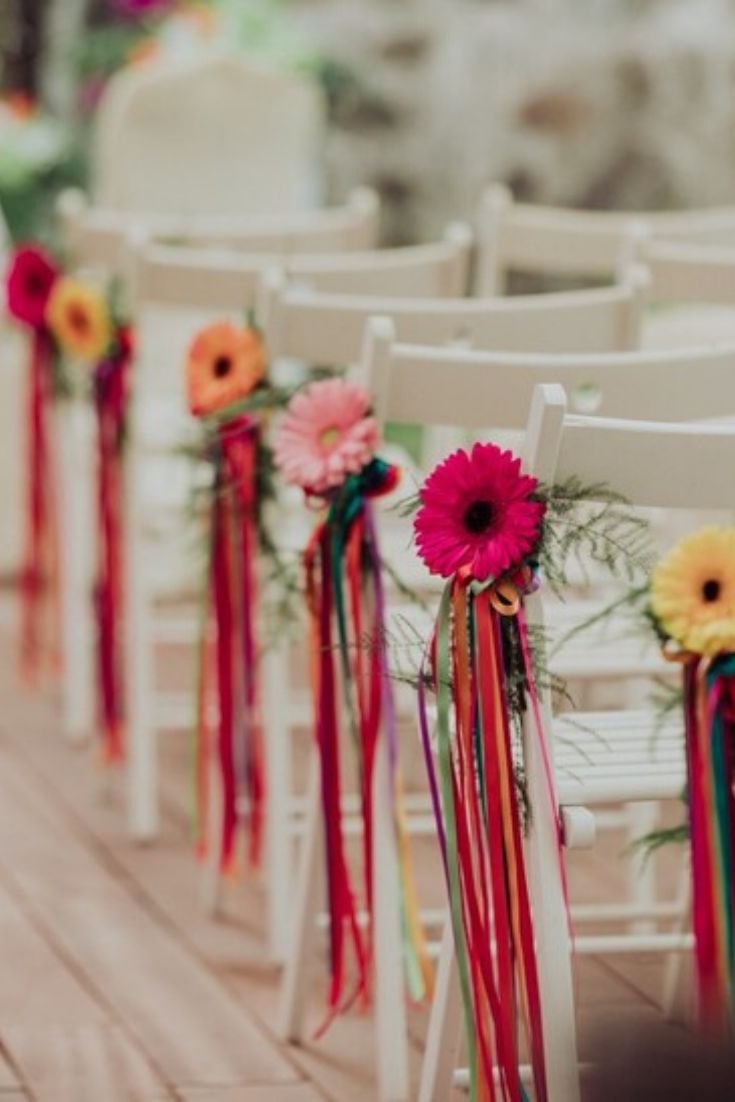 rows of white chairs decorated with colorful ribbons and flowers