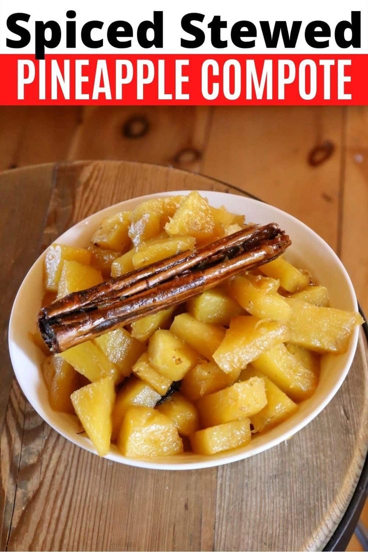 a bowl filled with sliced pineapple next to a plate of sausages and potatoes