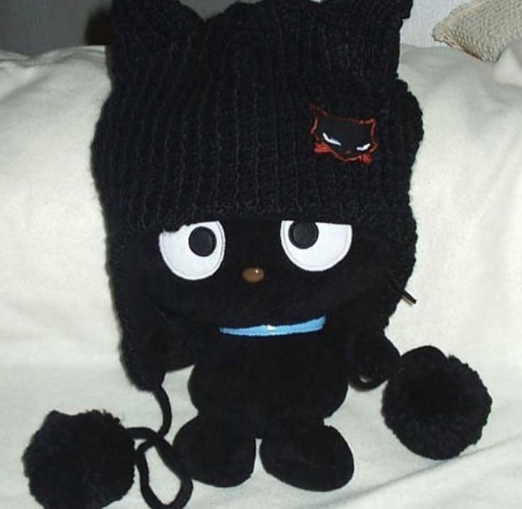 a black cat stuffed animal sitting on top of a bed