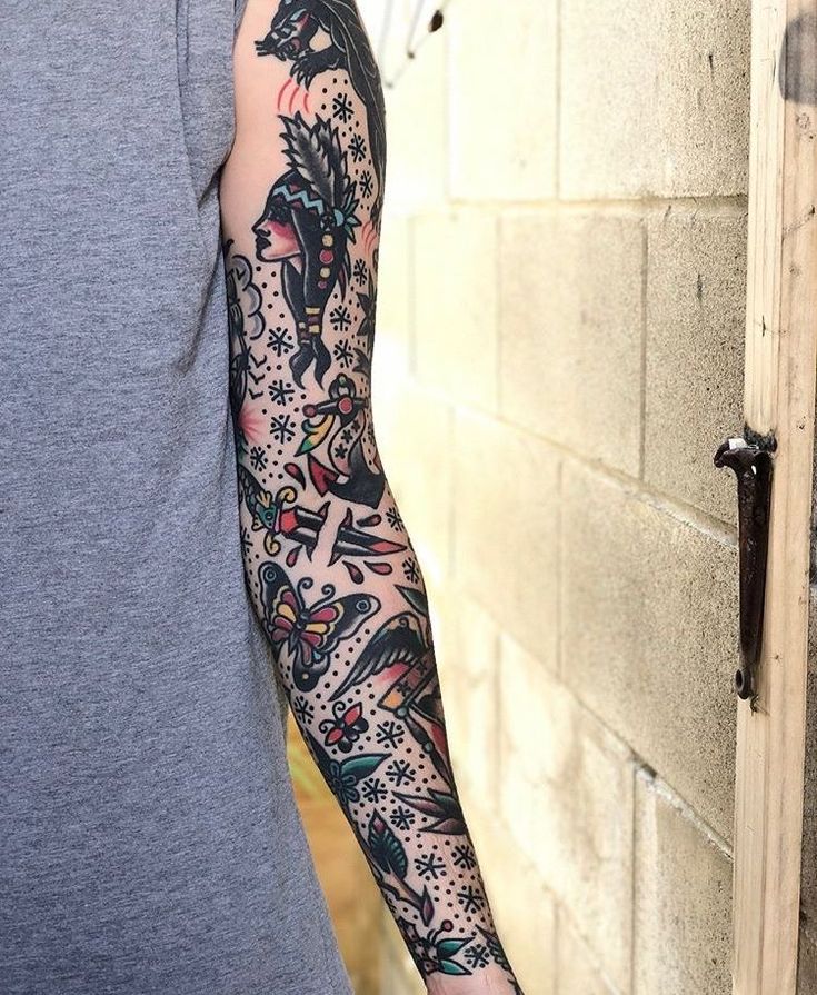 a man with a tattoo on his arm standing next to a brick wall and door