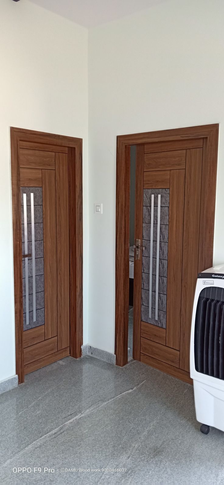 an empty room with two wooden doors and a dishwasher in the corner on the floor