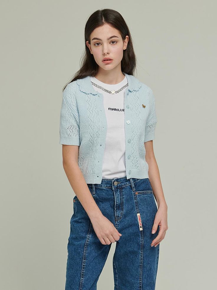 a young woman is standing wearing jeans and a white t - shirt with an embellishment on the chest