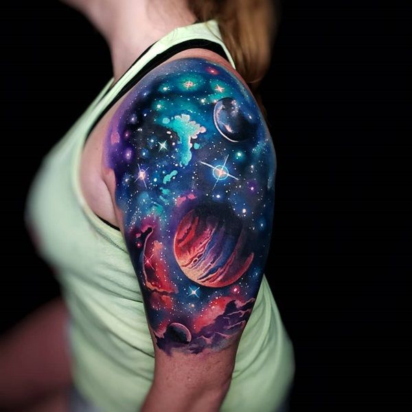 a woman with a colorful sleeve tattoo on her arm and shoulder is looking at the sky