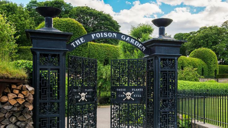 an iron gate that has the words the prison garden on it and is surrounded by trees