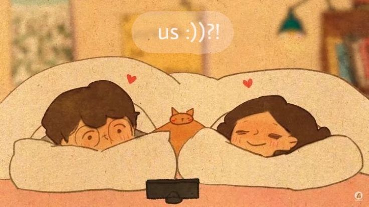 two people laying in bed with a cat