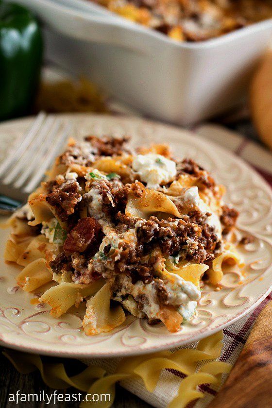 a white plate topped with pasta and meat covered in sauce next to a casserole dish