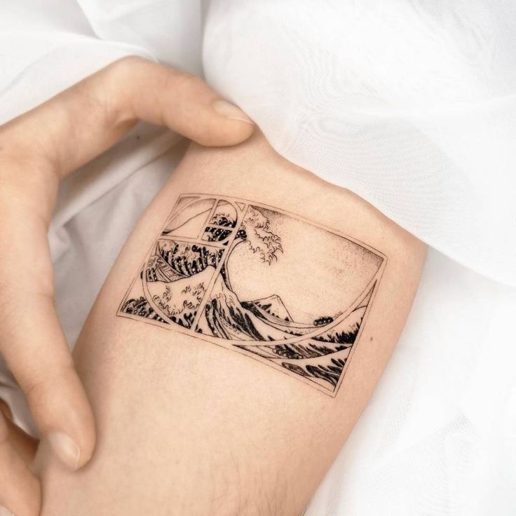 a person with a tattoo on their arm holding onto a white sheet and the image of an ocean wave