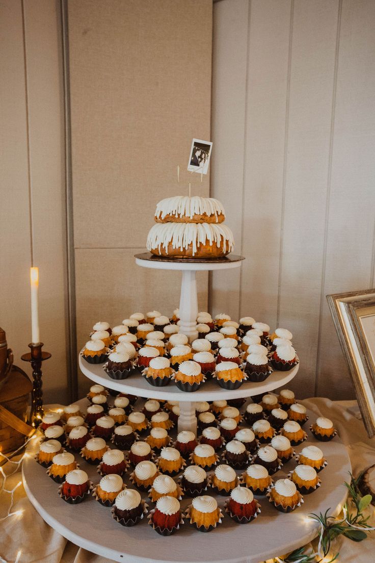 a three tiered cake and cupcake display on a table