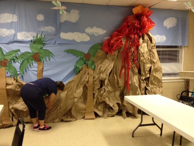 a woman bending over in front of a wall covered with paper mache and palm trees