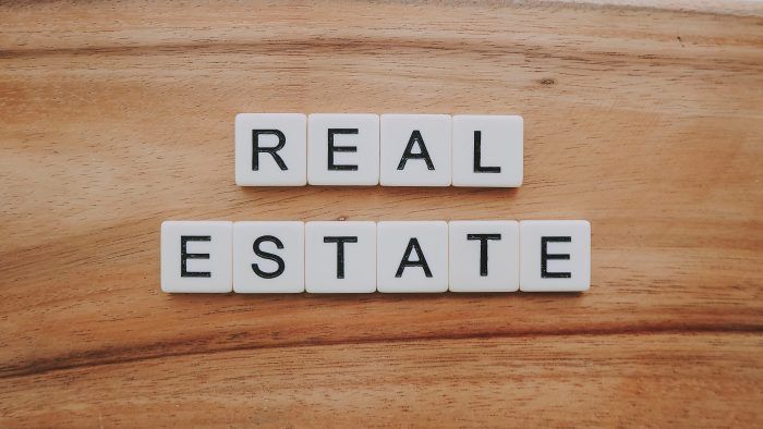 the word real estate spelled with scrabble blocks on a wooden surface, top view