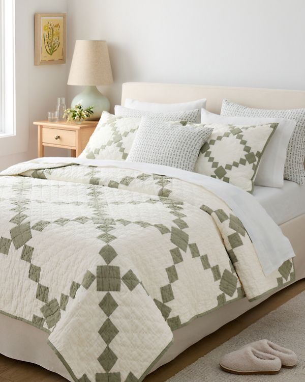 a bed with white and green bedspread in a bedroom