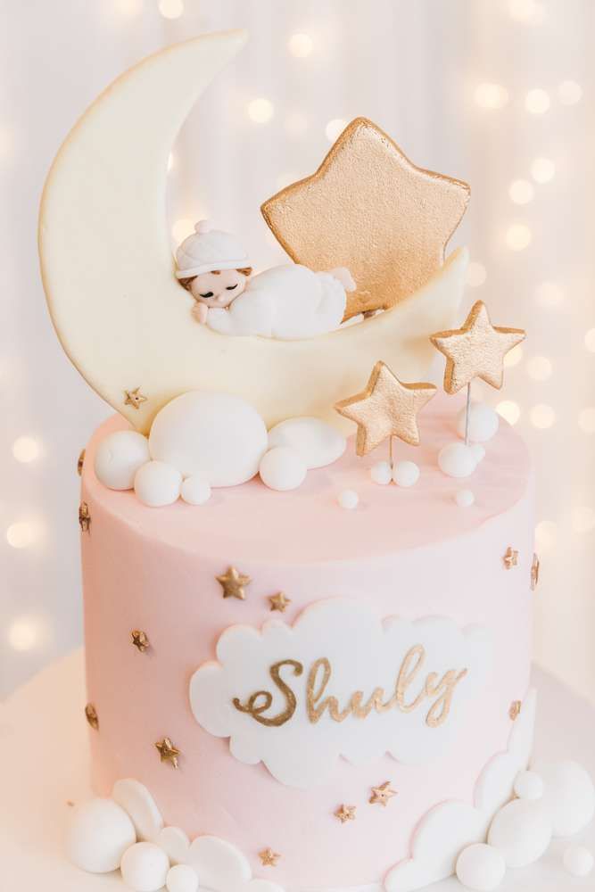 a pink cake with gold stars and a teddy bear on top