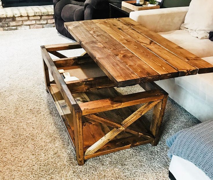 a wooden table sitting on top of a carpeted floor next to a white couch