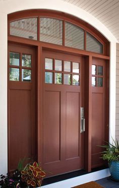 the front door is painted brown and has two planters