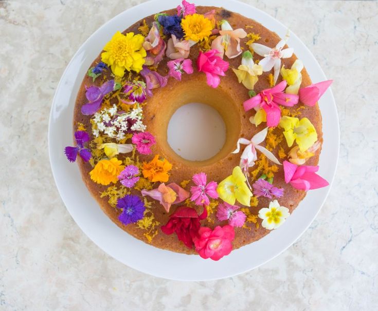 a bundt cake with flowers on it sitting on a white plate, ready to be eaten