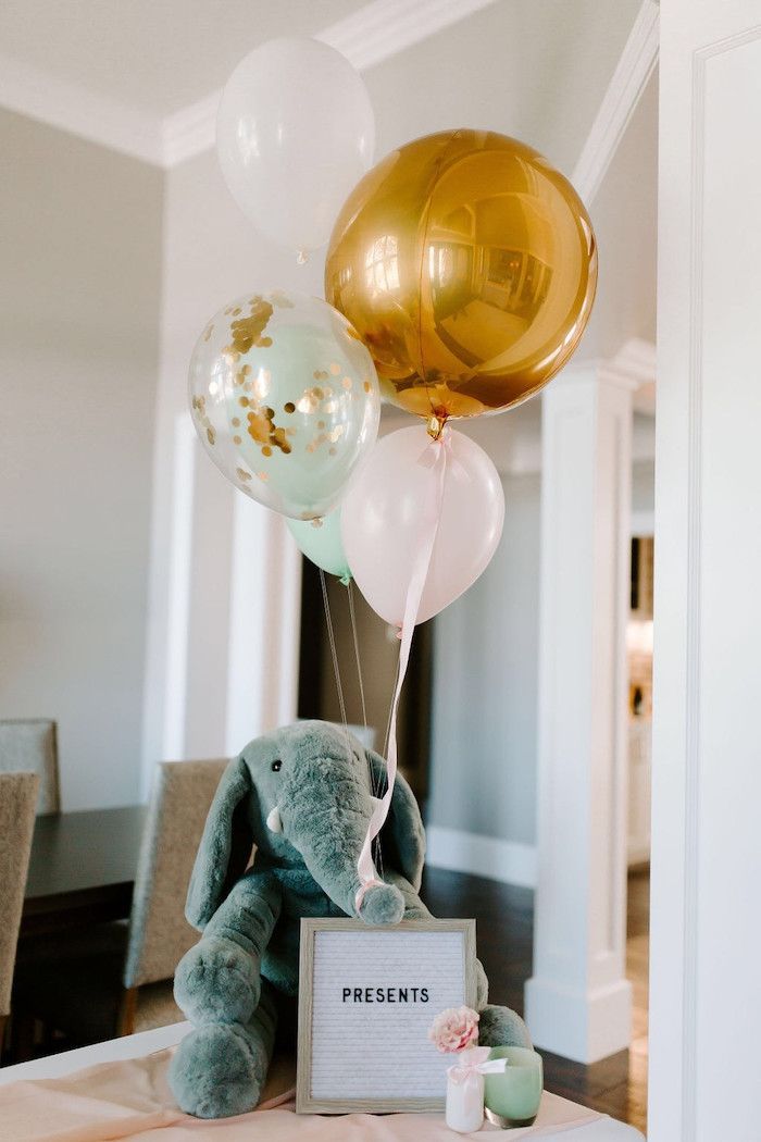 a teddy bear sitting on top of a table with balloons