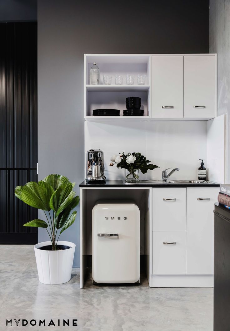 a kitchen with white cabinets and a black counter top next to a potted plant