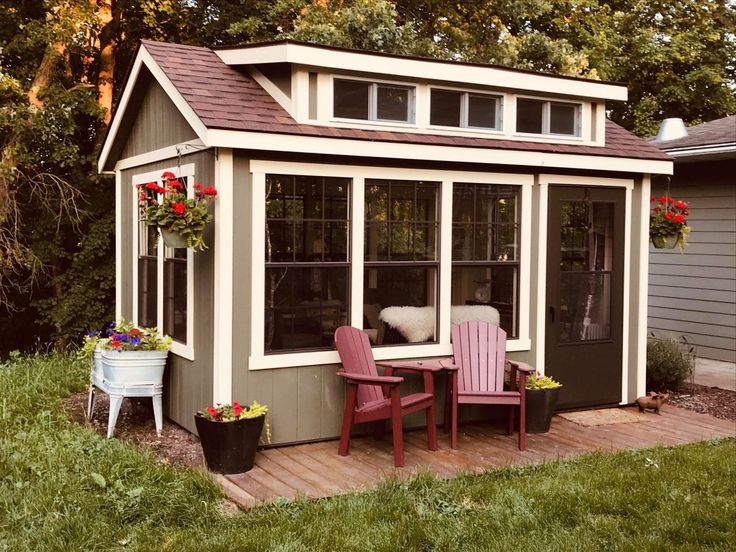 a small backyard shed with two chairs on the porch