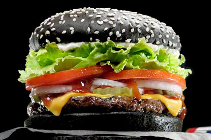 a cheeseburger with lettuce, tomato and onion on a black background