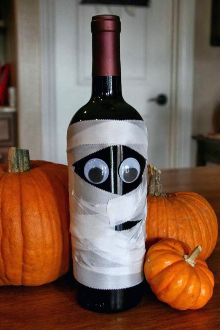 a bottle that has been wrapped in tape and is sitting on a table next to pumpkins