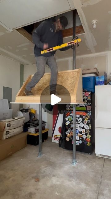 a man standing on top of a wooden table in a room with boxes and other items