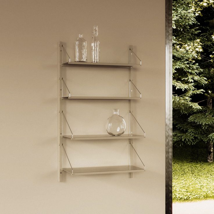 two shelves with glass vases on them in front of a tree and grass area