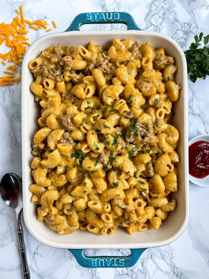 a casserole dish with sausage and pasta in it on a marble countertop