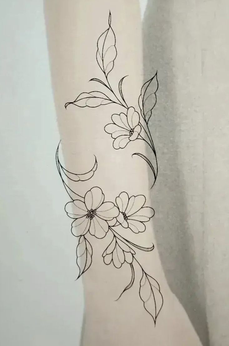 a woman's arm with flowers and leaves tattoo on the back of her leg