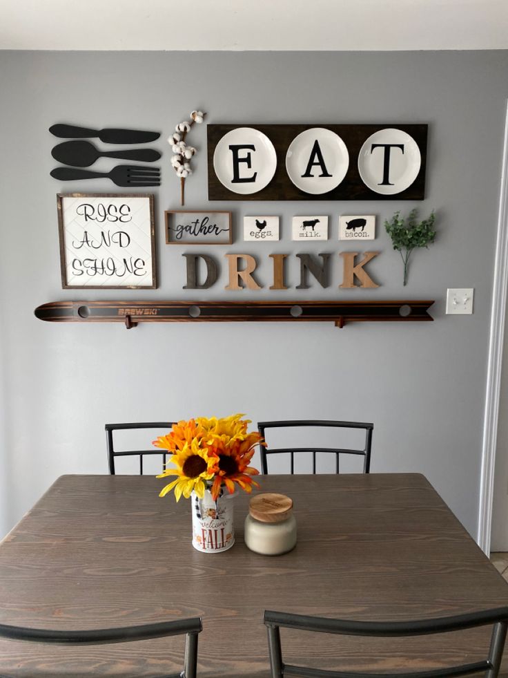 a dining room table and chairs with plates on the wall above it, sunflowers in a vase